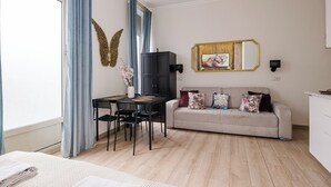 Un salon moderne comprenant un coin repas, un canapé agrémenté de coussins décoratifs, un miroir mural et un élément décoratif fixé au mur.