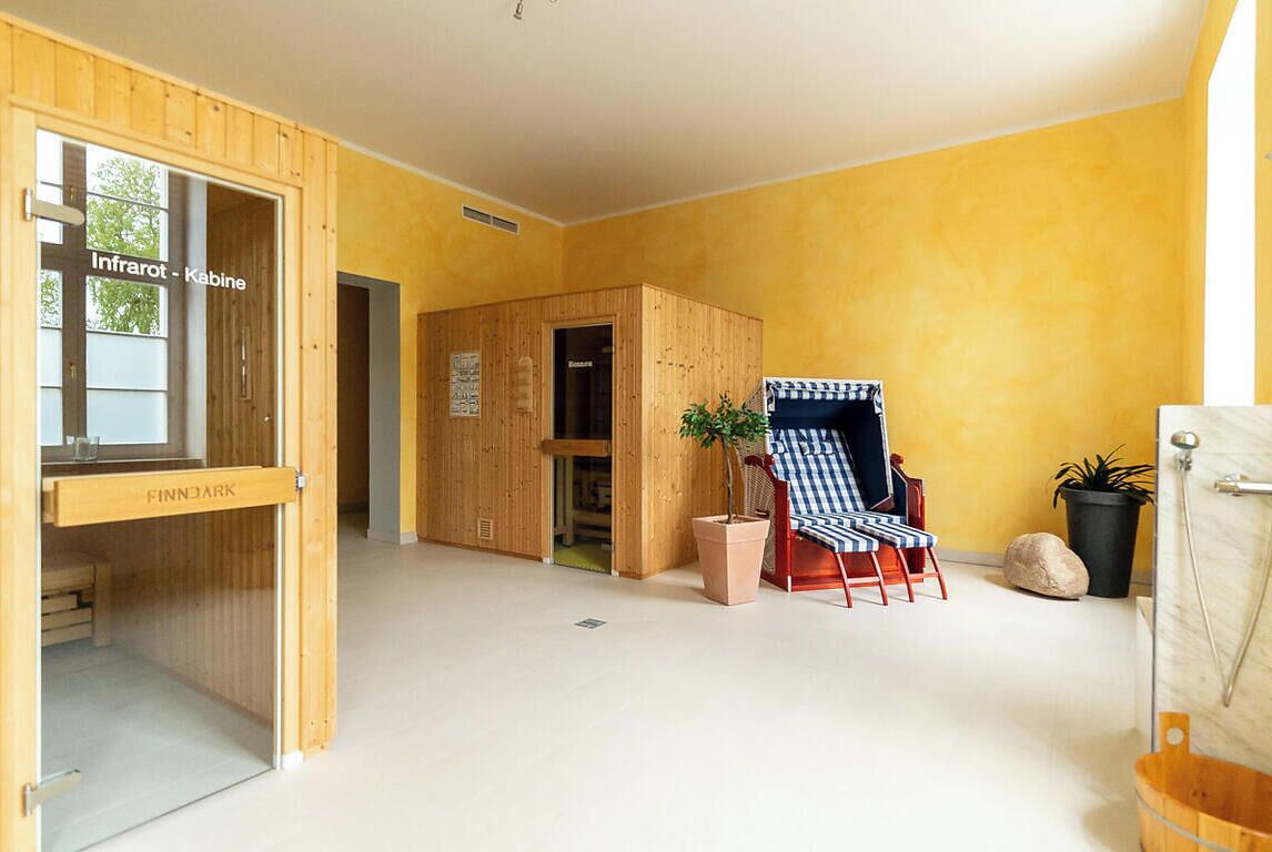 Een kamer met een houten sauna, een bankje en een potplant.