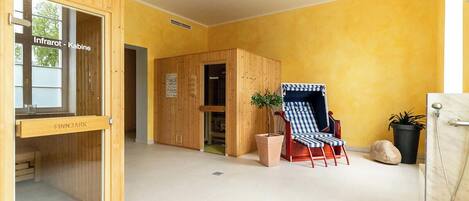 Een kamer met een houten sauna, een bankje en een potplant.