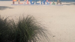 Ein Strand, auf dem der Schriftzug 'PLACENGIA' in bunten Buchstaben geschrieben ist.