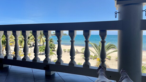 Ein Balkon mit Blick auf einen Strand und Palmen.