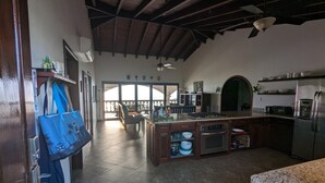 Uma cozinha espaçosa com uma ilha grande, uma área de jantar com vista e um ventilador de teto.