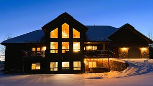 A large, multi-story lodge with a prominent front entrance and a balcony. - Spacious Cabin with Hot Tub, Fire Pit, Game Room (Island Park,)