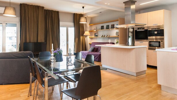 A modern kitchen with stainless steel appliances, a dining area with a glass table, and a living area with a sofa and curtains. - Upscale Kolonaki Experience Elegant Apt (Athens)
