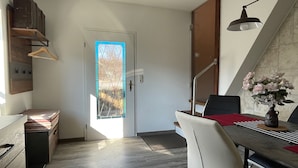 Una cucina moderna con zona pranzo, una scala e vista attraverso una porta in vetro.