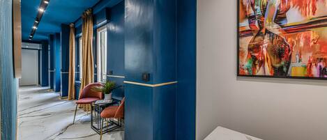 A hallway with a marble floor, blue walls, and a large abstract painting.
