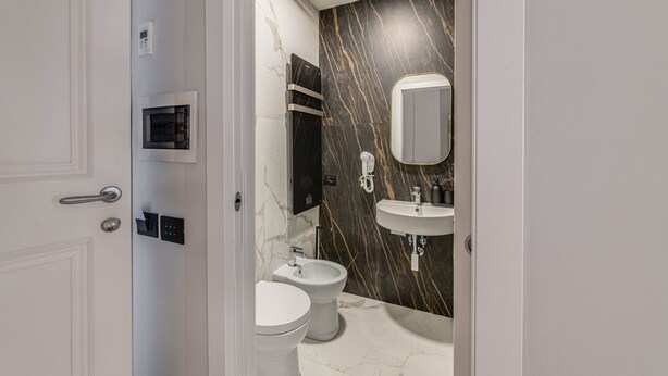 A modern bathroom with a marble wall, a built-in sink, and a toilet. - 7heaven pontevecchio rooms (Florence)