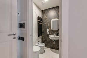 A modern bathroom with a marble wall, a built-in sink, and a toilet. - 7heaven pontevecchio rooms (Florence)