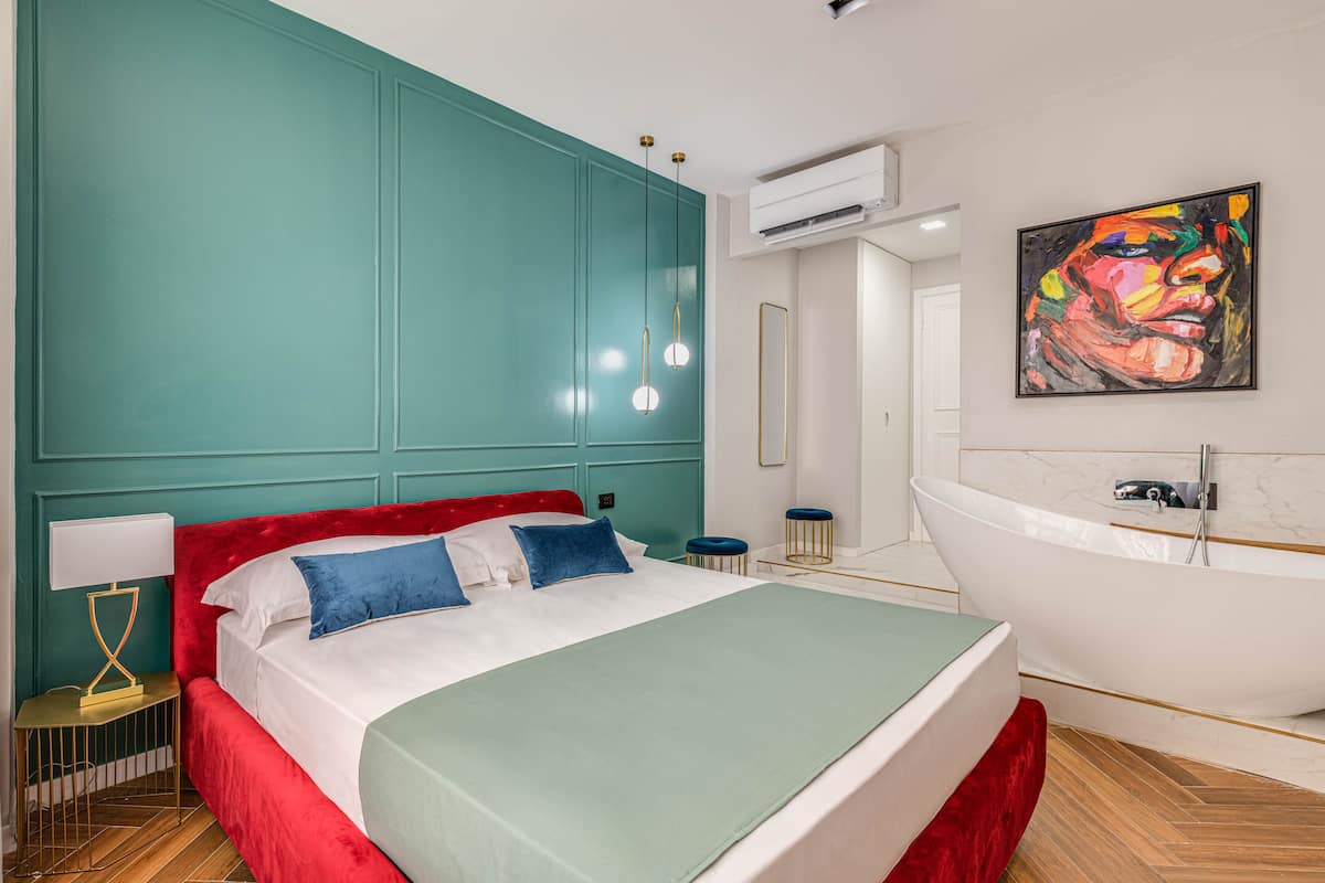 Een moderne slaapkamer met turquoise wanden, een rode bed en een witte badkuip.