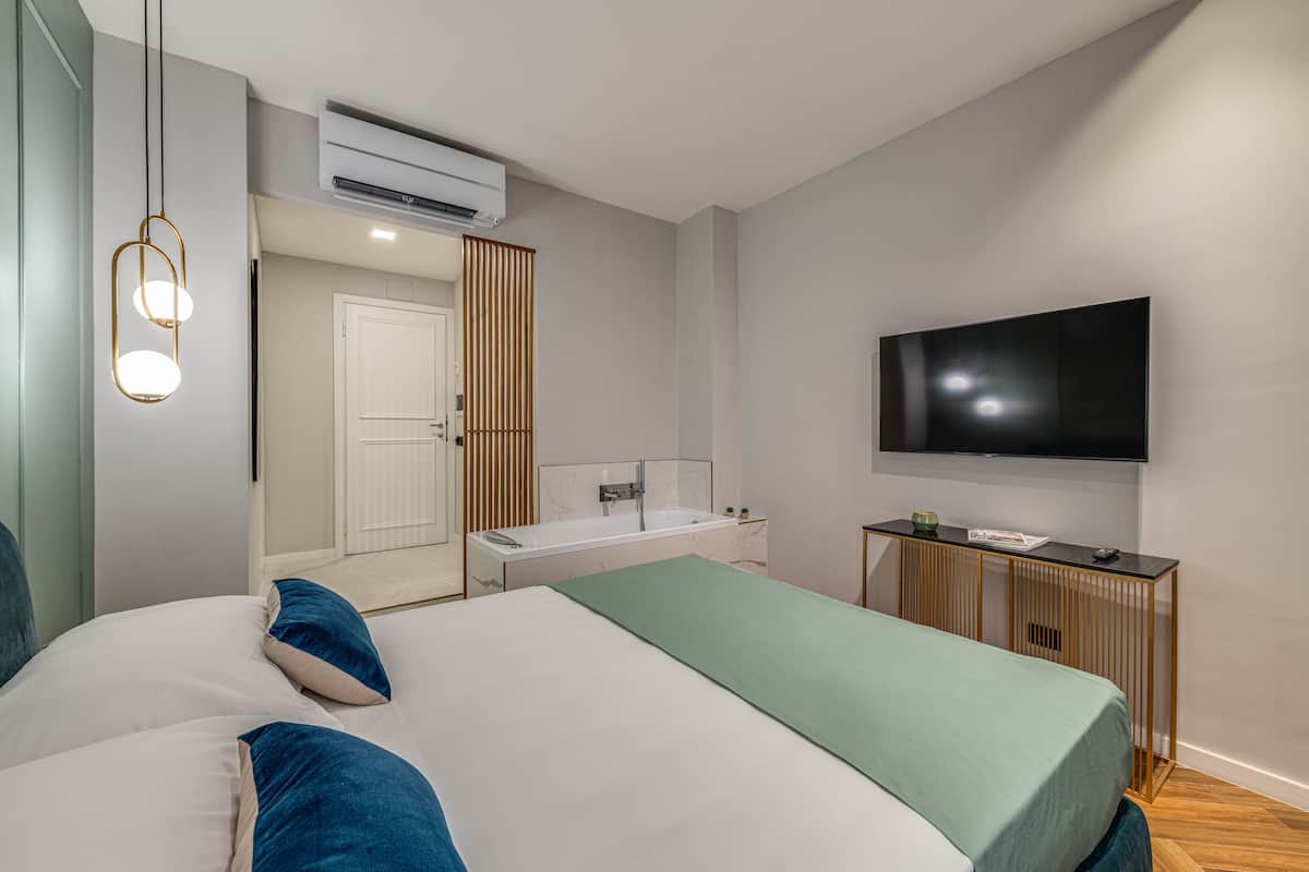 Een moderne slaapkamer met een groot bed, een televisie en een badkamer met een bad.