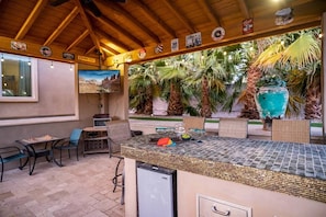 A bar area with a tiled counter, seating, and a small refrigerator.