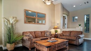 A living room with a sectional sofa, a wooden coffee table, and a large mirror on the wall. - Welcome to Paradise | Pool Table, Swim Up Bar, Htd Pool, Hot Tub, Casita! (Mesa)