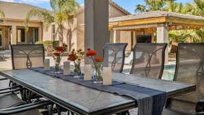 An outdoor dining area with a table set for four, surrounded by chairs. - Welcome to Paradise | Pool Table, Swim Up Bar, Htd Pool, Hot Tub, Casita! (Mesa)