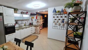 A kitchen with white cabinets, a stainless steel refrigerator, a built-in oven, and a dining area with a wooden table and chairs. - The private house Beer Sheba (Beersheba)