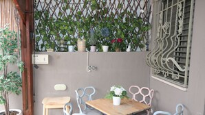 A small patio with a wooden table and chairs, surrounded by potted plants and a decorative metal fence. - The private house Beer Sheba (Beersheba)