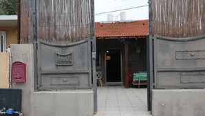 A building entrance with a tiled roof, a metal gate, and a small step leading inside. - The private house Beer Sheba (Beersheba)