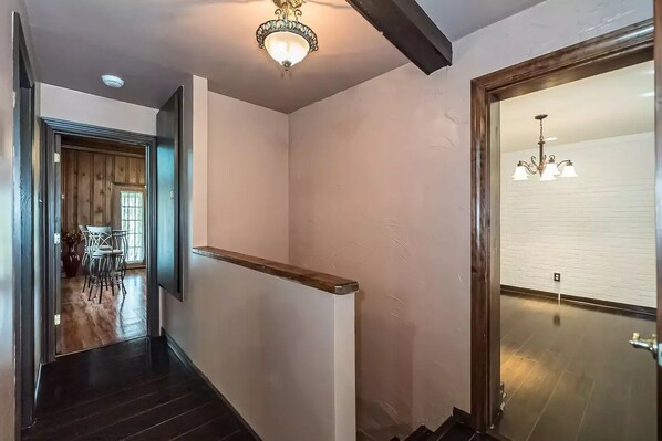 A hallway with a wooden staircase, a chandelier, and a dining area with chairs and a table.