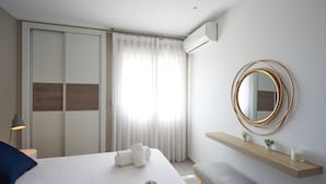 A modern hotel room with a bed, a bench, a mirror, and a shelf with plants. - Bright & Modern apartment 300m to the beach, tennis court and pools in Marbella (Marbella)