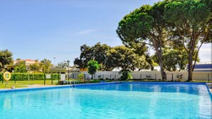 A swimming pool with clear blue water, surrounded by trees and a fence. - Bright & Modern apartment 300m to the beach, tennis court and pools in Marbella (Marbella)