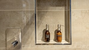 A bathroom with a mirror, two bottles of hair and body wash, and a soap dispenser. - The Old Stables - Luxury Dartmouth town centre apartment w/ parking permit (Dartmouth)