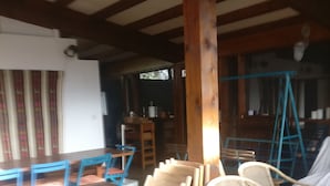 Ein Essbereich mit Holztischen und -stühlen, einer Holzsäule und einer Schaukel.