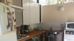 Eine kleine Küche mit weißen Schränken, einer integrierten Mikrowelle, einem kleinen Kühlschrank und einem Spülbecken.
