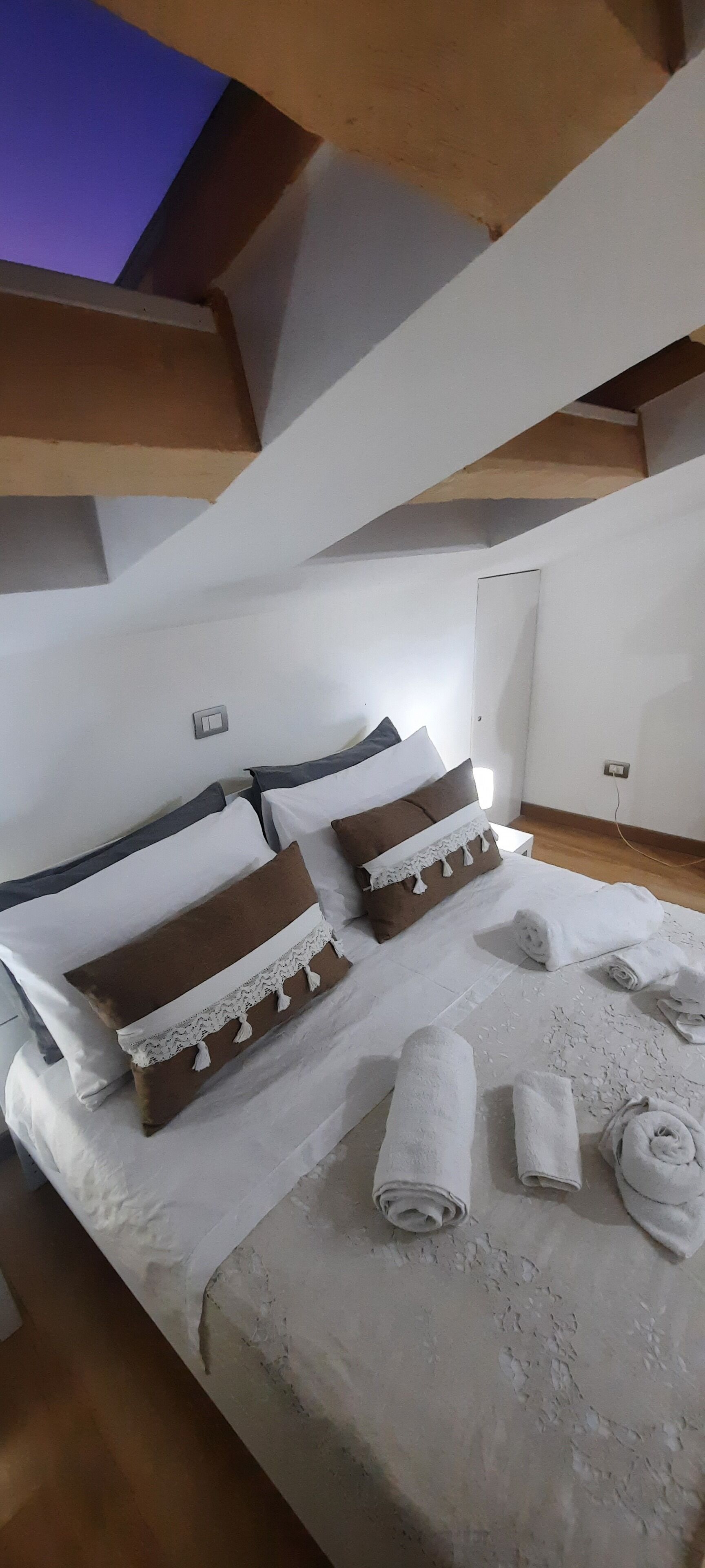 Une chambre à coucher avec un lit, des oreillers et des serviettes enroulées.