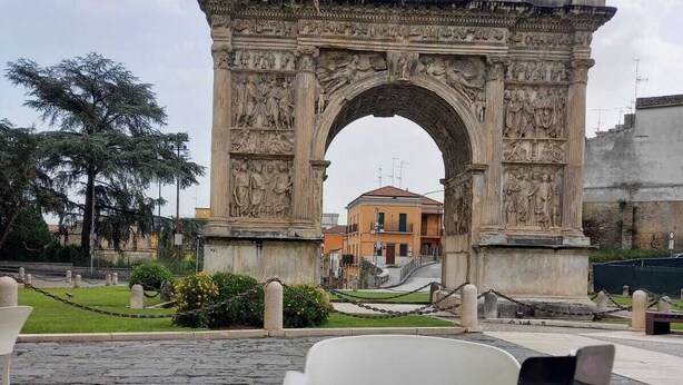 A table with a croissant and a cup, set against a backdrop of an ancient archway with detailed carvings. - La Mansarda Suite (Benevento)