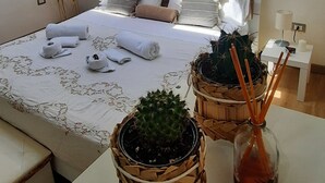 A modern bedroom with a skylight, a neatly made bed, and two potted plants. - La Mansarda Suite (Benevento)