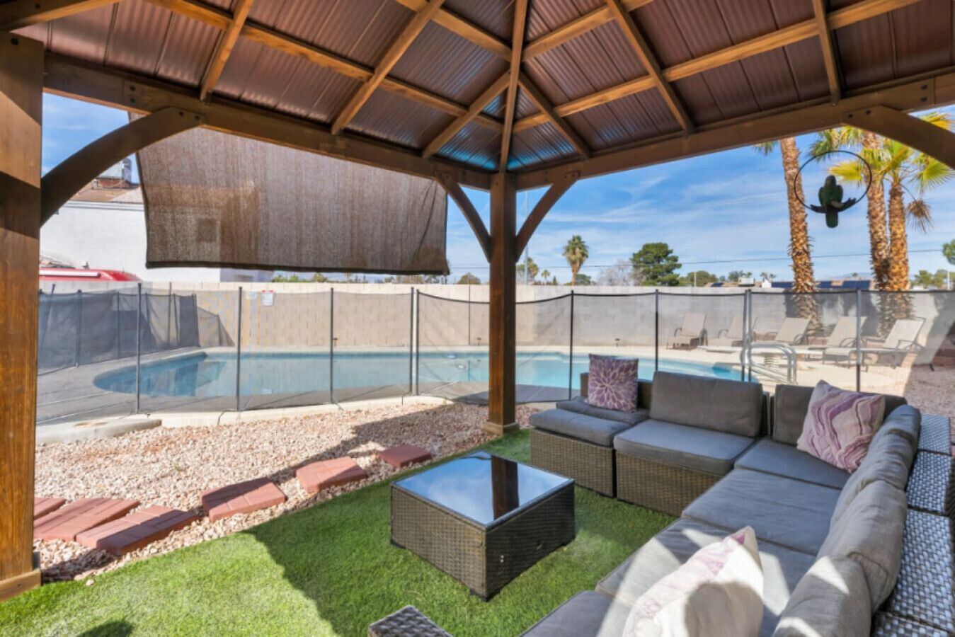 A covered outdoor area with a pool, seating, and a pergola.