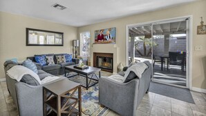 A living room with a gray sofa set, a coffee table, a fireplace, and a sliding glass door leading to an outdoor patio.