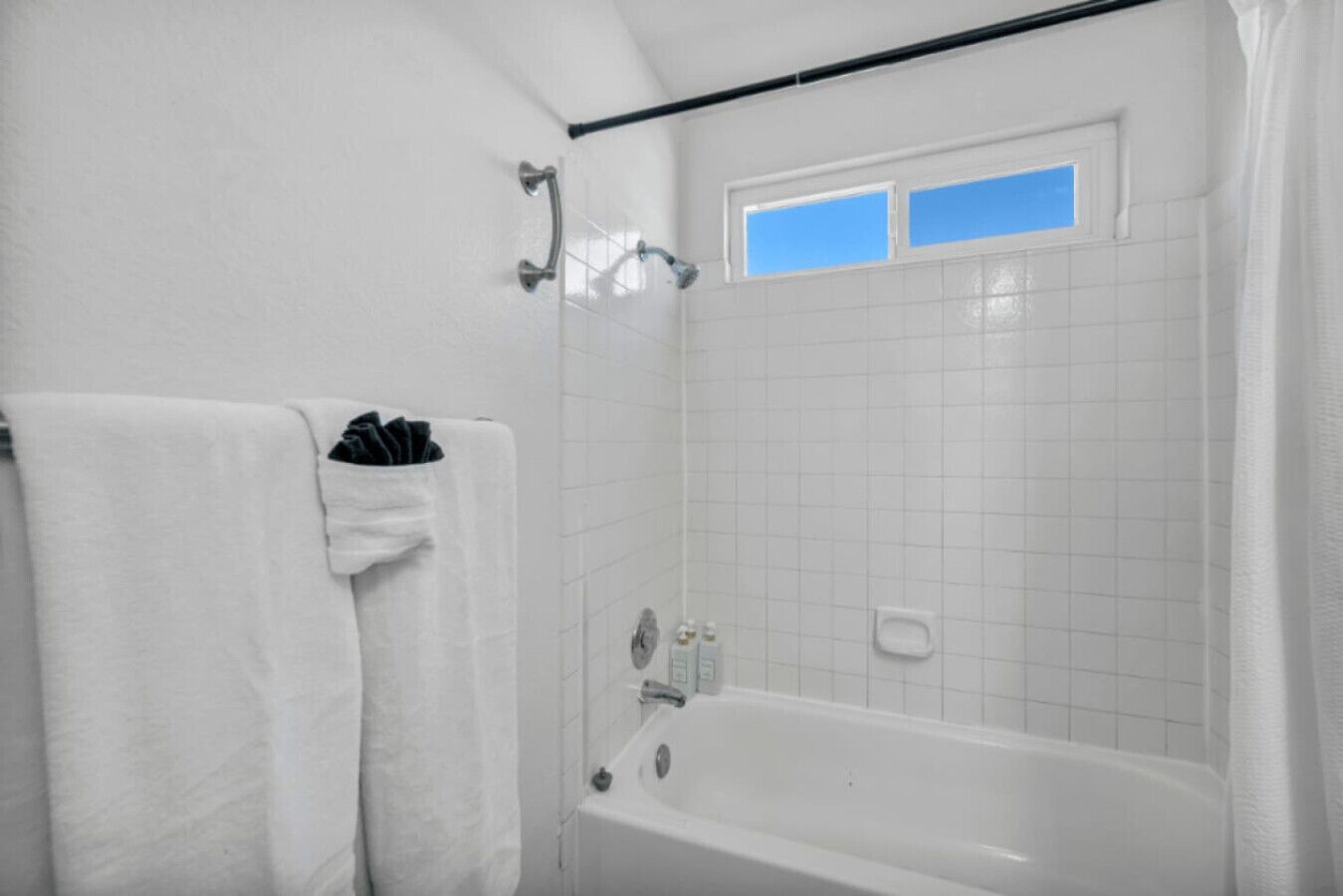 A bathroom with a bathtub, a window, and a towel rack.