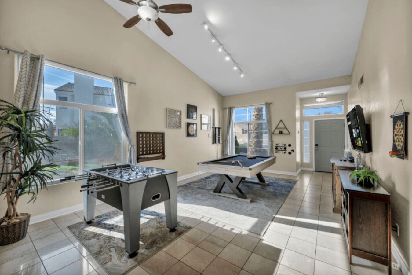 A spacious room with a foosball table, pool table, and ceiling fan.