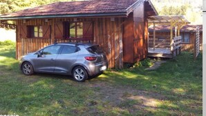 A rustic wooden cabin with a porch and a car parked in front. - Agréable Chalet Nature Calme (Cornimont)