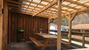 Una struttura in legno con un tavolo da picnic e un cestino verde.