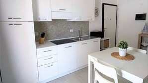 Une cuisine moderne avec des meubles blancs, un îlot central et une table à manger avec des chaises.
