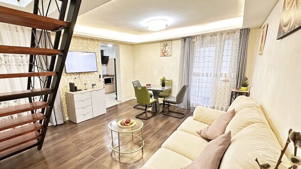 Uma sala de estar moderna com um sofá, uma mesa de jantar e uma escadaria.