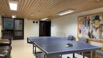 A ping pong table in a room with a wooden ceiling and a painting on the wall.