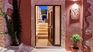 A hotel entrance with a stone facade, a staircase leading inside, and a signboard with the hotel name. - Vin Dimora Suites with shared pool - Vino Roze (Ano Archanes)