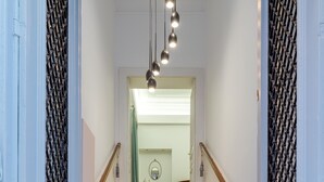 A staircase with red carpeted steps leading to a room with a white door and a light fixture above. - Superior Suite Theseus by 2 Mazi Suites (Athina)
