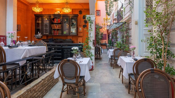 An outdoor dining area with tables and chairs, a bookshelf, and a chandelier. - Superior Suite Theseus by 2 Mazi Suites (Athina)