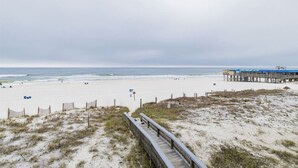 Una playa con un paseo marítimo de madera que conduce a un muelle con techo azul.