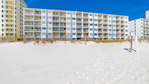 Un hotel frente a la playa con varios balcones y una playa arenosa al frente.
