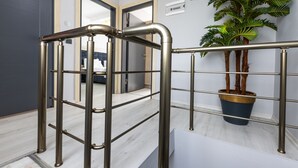 A metal handrail with a grid design, a potted plant, and a door in the background. - LİFE POOL SUİTE HOTEL (Trabzon)