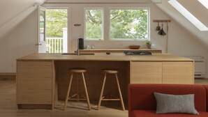 A compact, modern loft apartment with a kitchen area, a dining space, and a cozy seating area.
