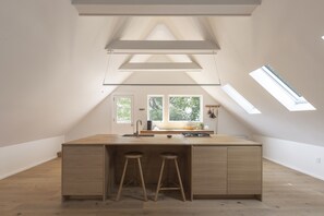 Une cuisine moderne dotée d’un îlot central, de deux tabourets, de fenêtres de toit et offrant une vue sur l’extérieur.