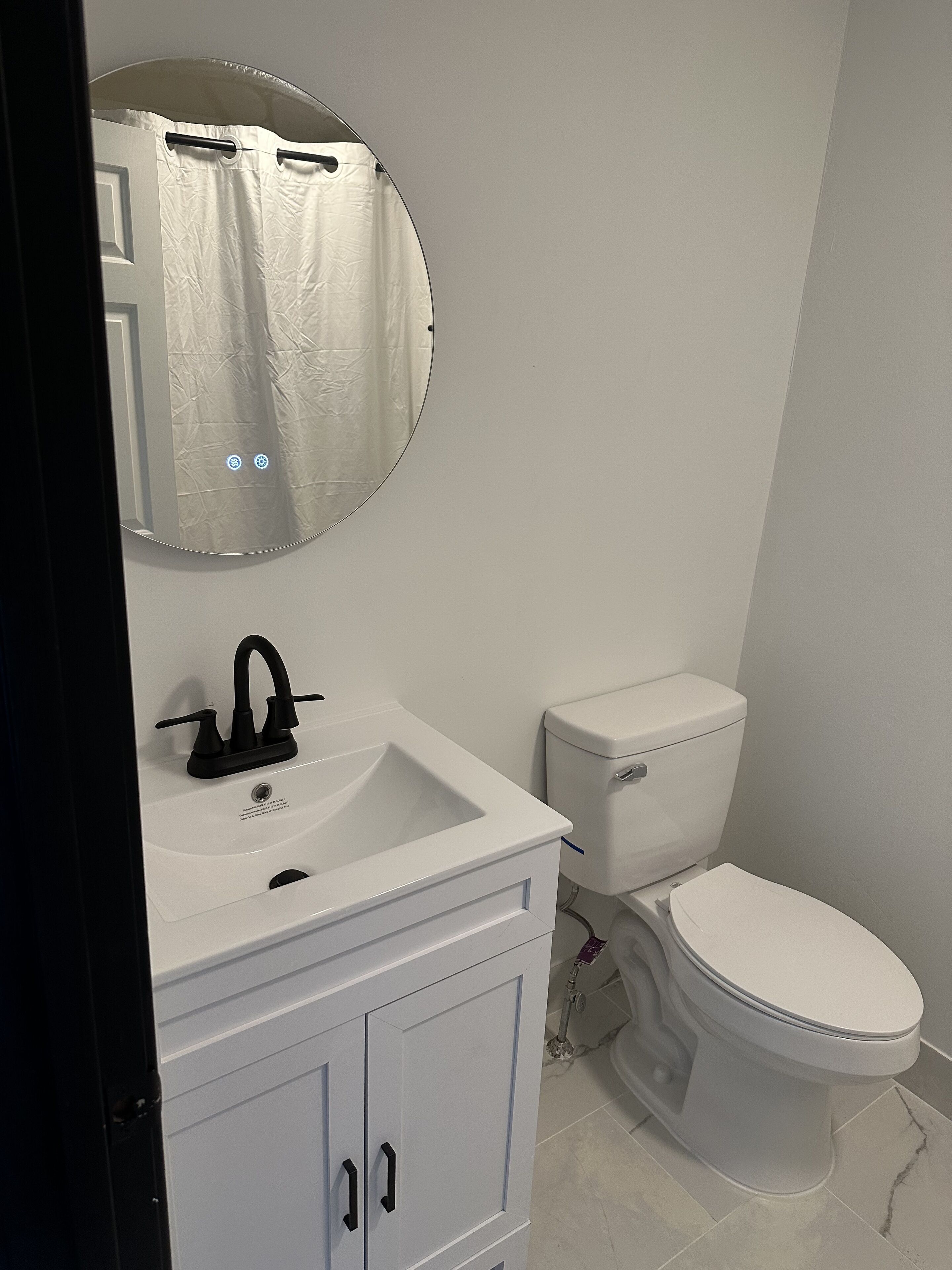 Un baño con un lavamanos blanco, grifo negro y un inodoro.