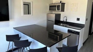 A compact kitchen with a central island, a microwave, a refrigerator, and a sink. - Harborside Suites (South Yarmouth)