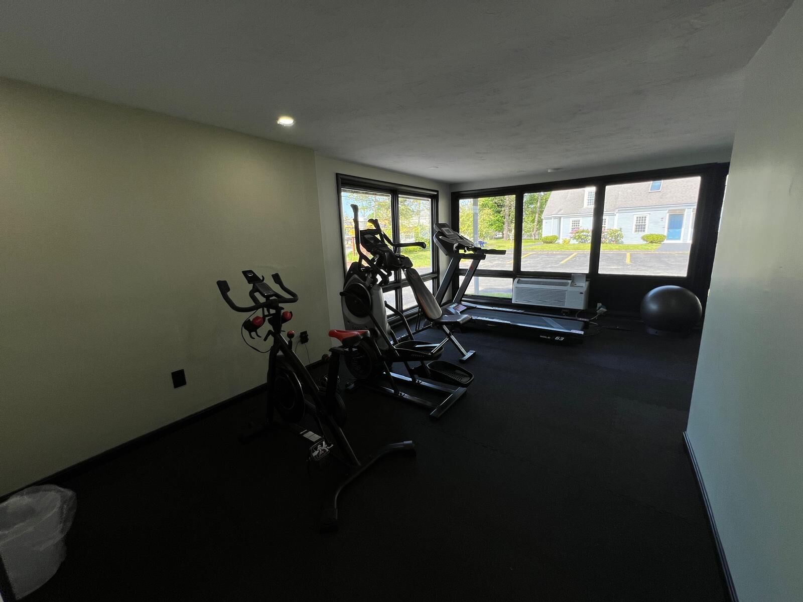 A gym with stationary bikes, a treadmill, and a large exercise ball.