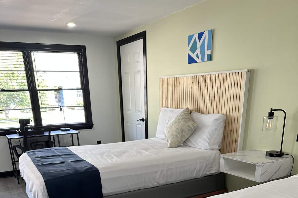 A hotel room with two beds, a desk, and a chair.